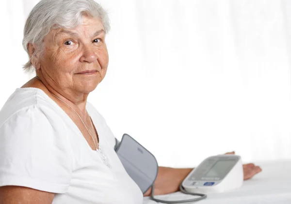 Mujer anciana midiendo la presión arterial con manómetro automático —  Fotos de Stock