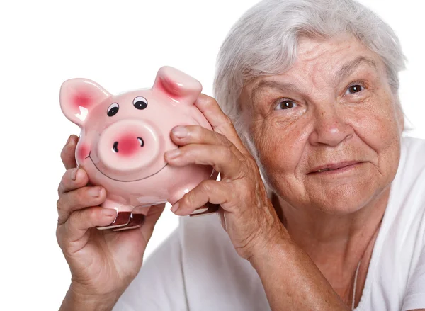 Elder woman holding and hugging funny pink piggybank. Budgeting expenses, making savings, effective investment concept. Future needs deposit. Focus on pig. Retirement and retiree finansial problems