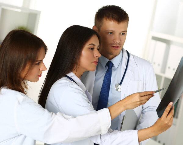 Three medicine doctors examining x-ray photography