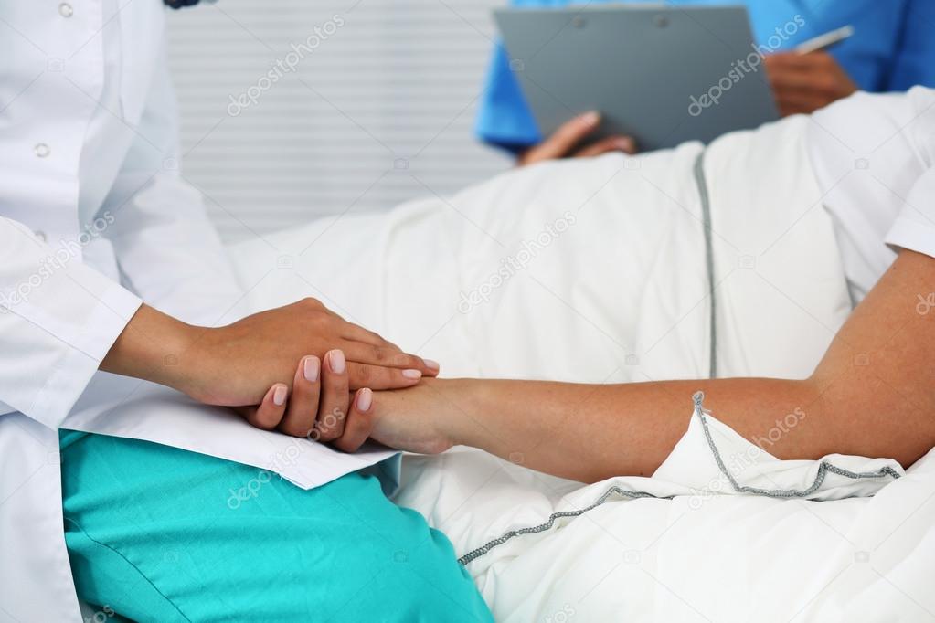 Friendly female doctor hands holding patient hand 