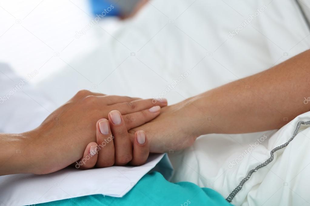 Friendly female doctor hands holding patient hand 