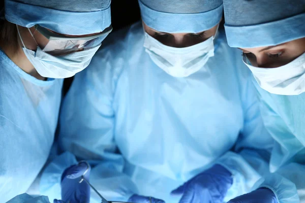 Group of surgeons at work operating in surgical theatre — Stock Photo, Image