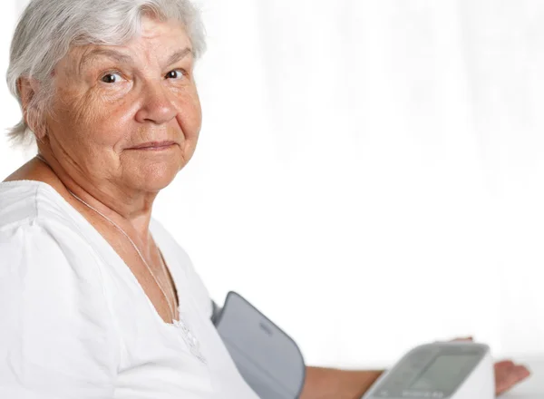 Elder woman measuring blood pressure — Stock fotografie