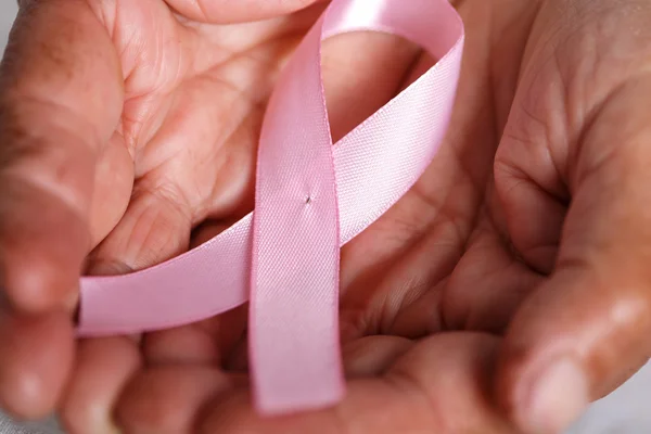 Elder woman hands holding pink ribbon — Stock Photo, Image