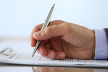 Hand of businessman in suit filling and signing partnership agre