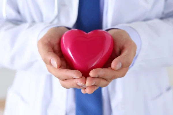 Férfi gyógyszer orvos kezét tartó és borító piros játék szív — Stock Fotó