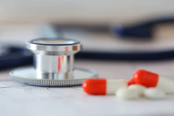 Medical stethoscope head lying on cardiogram chart — Stock Photo, Image