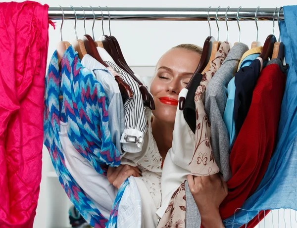 Vackra leende blond kvinna står inne i garderob rack — Stockfoto