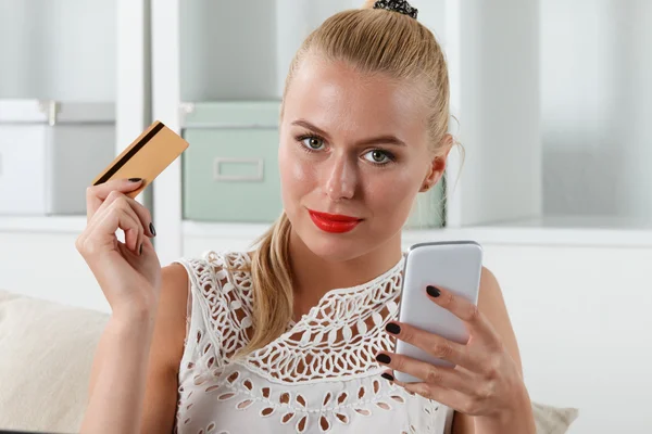 Beautiful blonde woman holding golden credit — Stockfoto