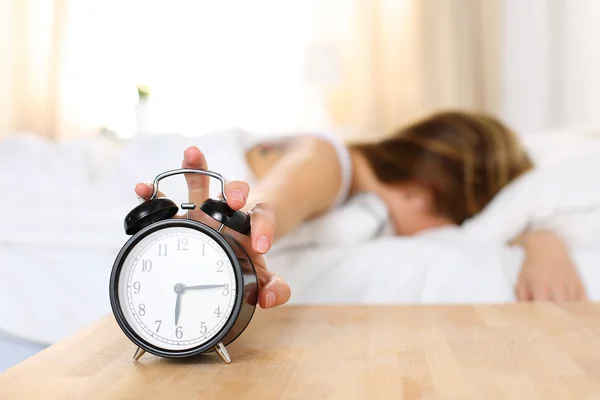 Jovem sonolenta tentando matar despertador — Fotografia de Stock