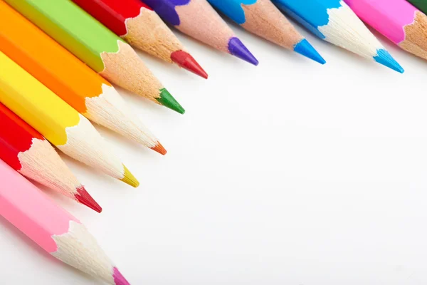 Набір різнокольорових олівців, що лежать на білому столі — стокове фото