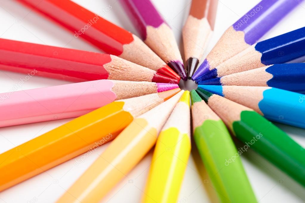Set of multicoloured pencils lying on white table round order