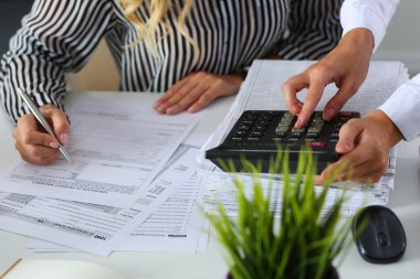 Two female accountants counting on calculator