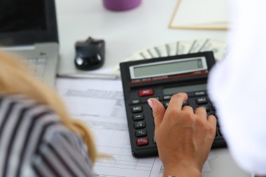 Two female accountants counting on calculator