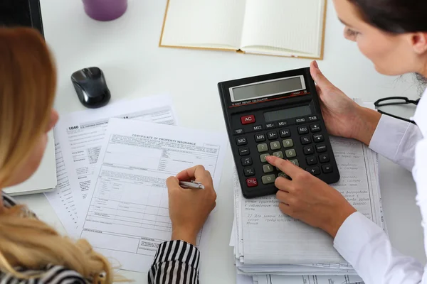 Two female accountants counting on calculator