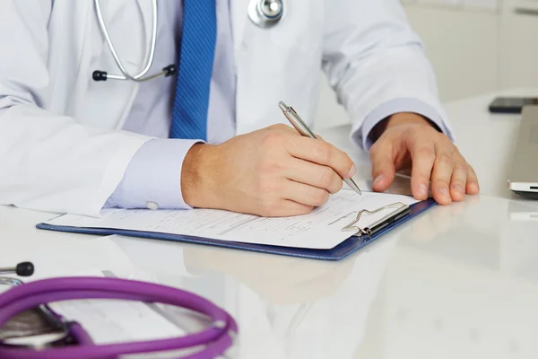 Médico de medicina masculina mãos preenchendo formulário de registro do paciente — Fotografia de Stock