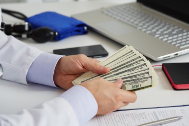 Yüz dolar b el avuç içinde tutan erkek tıp doktor
