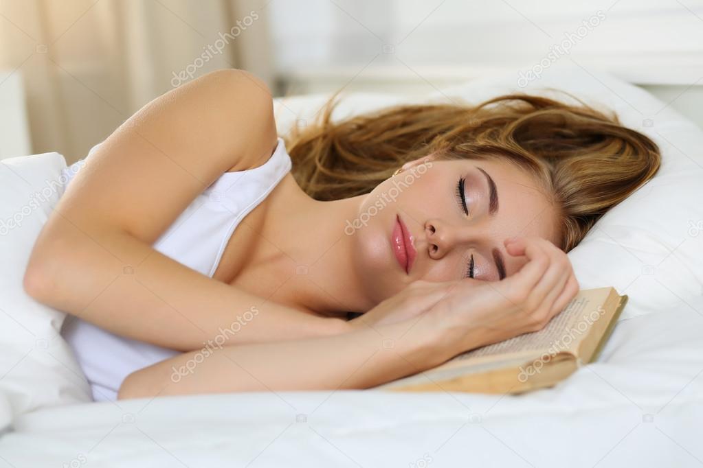 Young beautiful blonde woman portrait lying in bed sleeping on b