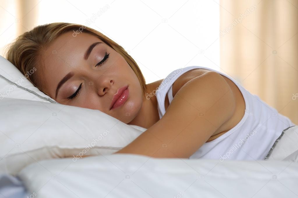 Young beautiful blonde woman portrait lying in bed sleeping