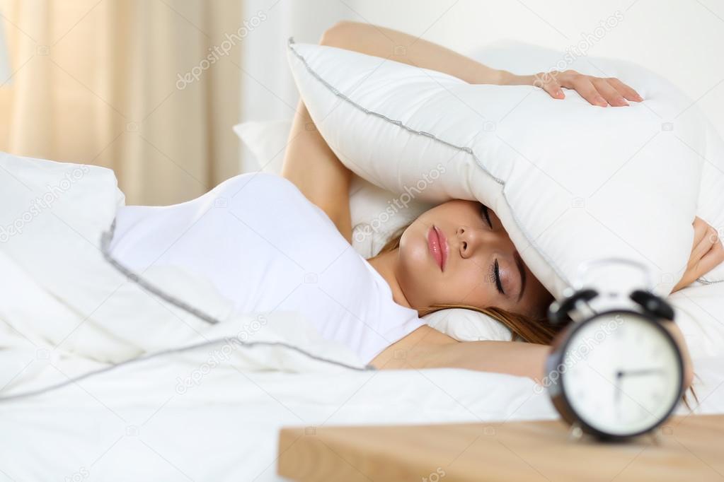 Young beautiful blonde woman lying in bed suffering from alarm c