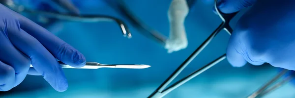 Cirurgiões mãos segurando instrumento cirúrgico — Fotografia de Stock
