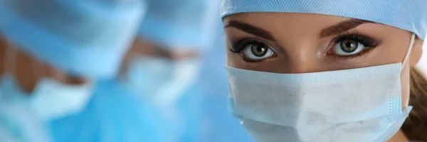 Tres cirujanos en el trabajo que operan en quirófano —  Fotos de Stock