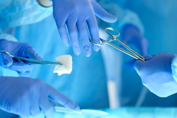 Cirujanos de manos sosteniendo y pasando el instrumento quirúrgico a otro — Foto de Stock