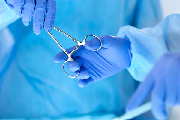 Surgeons hands holding and passing surgical instrument to other 