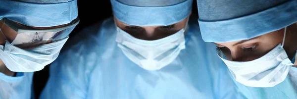 Três cirurgiões em trabalho operando em teatro cirúrgico — Fotografia de Stock