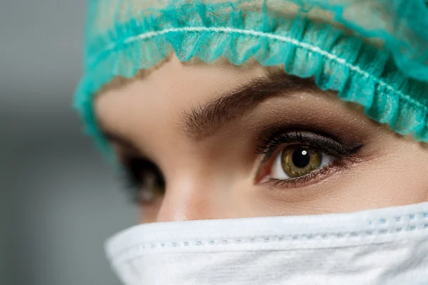 महिला डॉक्टर चेहरा सुरक्षात्मक मास्क और ग्रीन सर्जन टोपी पहने हुए — स्टॉक फ़ोटो, इमेज