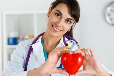 Güzel gülümseyen kadın doktor ch önünde kırmızı kalp tutan