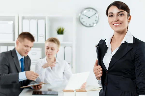 Hermosa mujer de negocios sonriente en traje sujetando portapapeles en ha — Foto de Stock