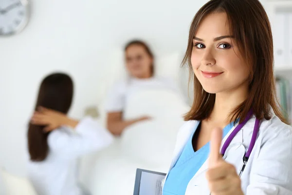 Sonriente médico femenino sosteniendo la almohadilla de documentos y mostrando — Foto de Stock