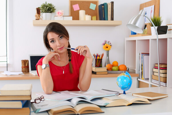 Female student at workplace with pile of textbooks