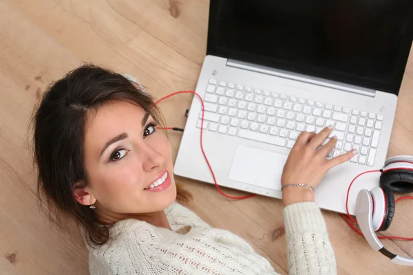 Mooie lachende vrouwelijke student liggend op houten vloer werken — Stockfoto