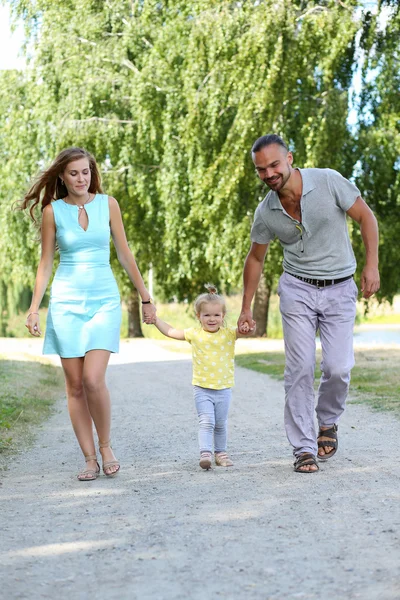Pais felizes com filha ao ar livre segurando as mãos — Fotografia de Stock