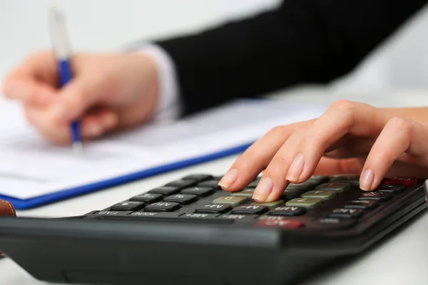 Женщина-бухгалтер держит ручку, рассчитывая на калькулятор — стоковое фото