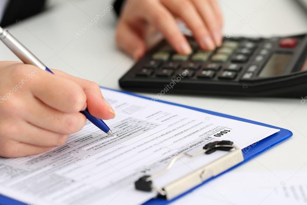 Female accountant hand holding pen counting on calculator