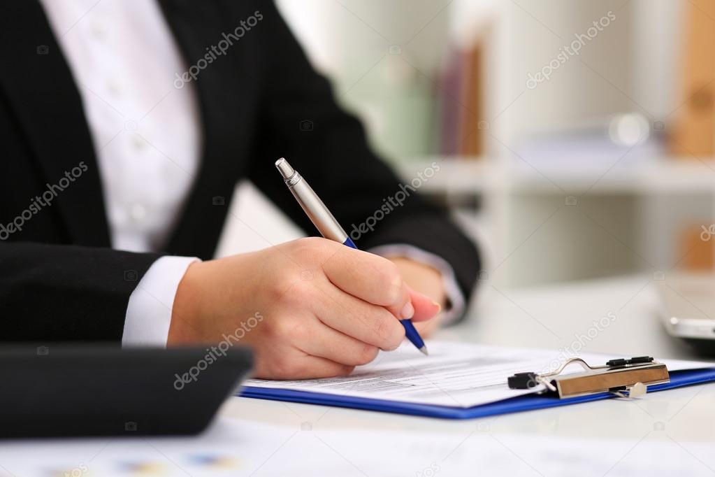 Hand of businesswoman filling and signing with silver pen partne