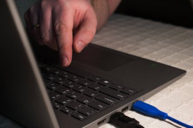 Dizüstü bilgisayarın tuş tahtasındaki tek parmak tuşuna basın. Elinizi dizüstü bilgisayarın tuş tahtasına koyun. Ev ofisinde çalışan adam..