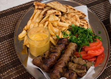 Geleneksel lamba kebabı. Taze salata, patates ve sosla hasır yüzeyde. Izgara et kebap. Üst görünüm.