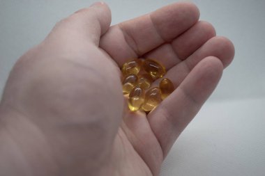 Balık yağı kapsüllerini tutan bir adam. Balık yağları sağlık hizmetleri için omega-3 içeren diyet takviyesi olarak kullanılıyor.
