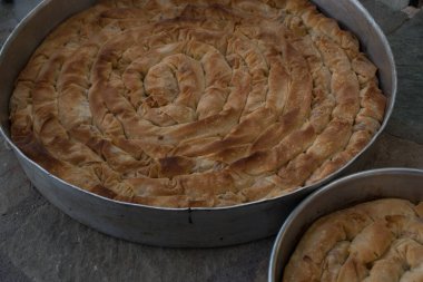 Filo, ıspanak, mizithra ve feta peynirli iki demir fırın tavasında ev yapımı geleneksel Yunan peynirli turta..