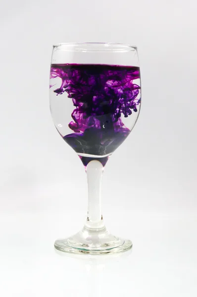 stock image Glass full of water with ink color drop