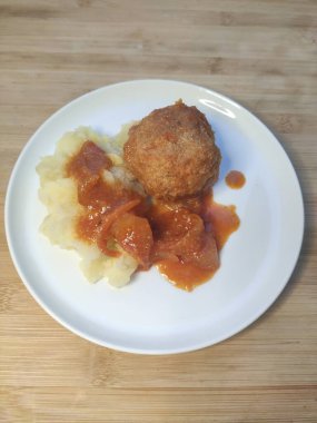 Masadaki beyaz tabakta patates püresi ile köfte.,