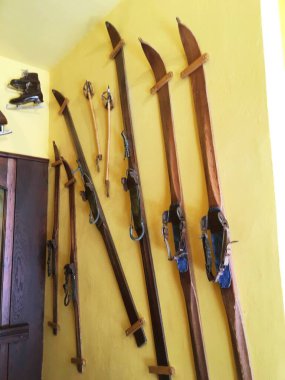 old skis and ski poles hang on the wall clipart
