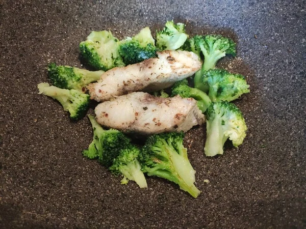 white fish with broccoli cooked in a frying pan