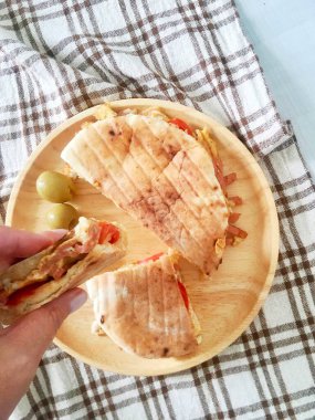 Kadının elindeki ahşap tabakta jambon ve peynirli pide.