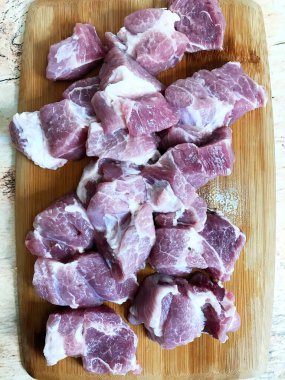 Tahta kesme tahtasının üzerinde doğranmış çiğ domuz filetosu.