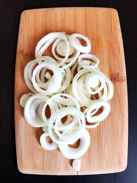 a white onion cut into rings on a wooden table